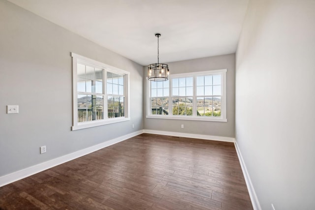 unfurnished dining area featuring a chandelier and dark hardwood / wood-style flooring