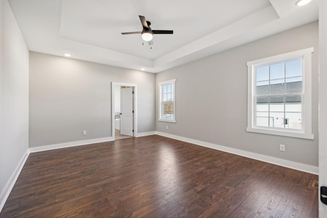 spare room with plenty of natural light, dark hardwood / wood-style floors, ceiling fan, and a tray ceiling