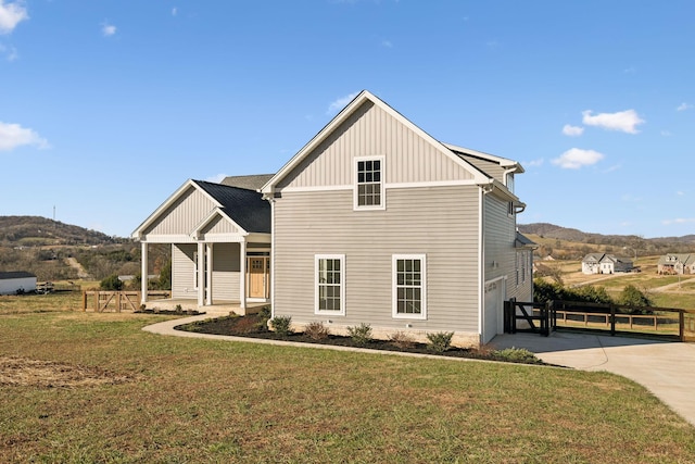 view of front of home with a mountain view, a porch, a garage, and a front lawn