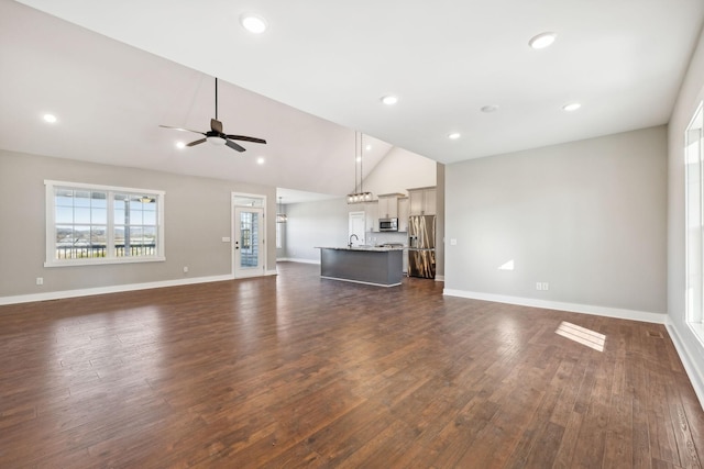 unfurnished living room with ceiling fan, dark hardwood / wood-style flooring, sink, and high vaulted ceiling