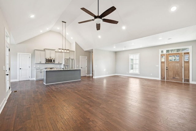 unfurnished living room with dark hardwood / wood-style flooring, high vaulted ceiling, ceiling fan, and sink