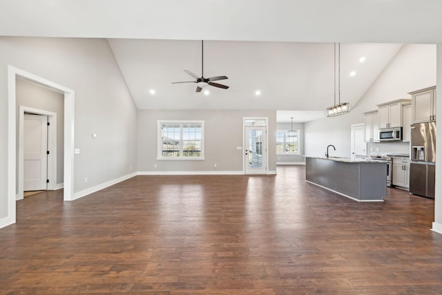 unfurnished living room with ceiling fan, dark hardwood / wood-style flooring, high vaulted ceiling, and sink