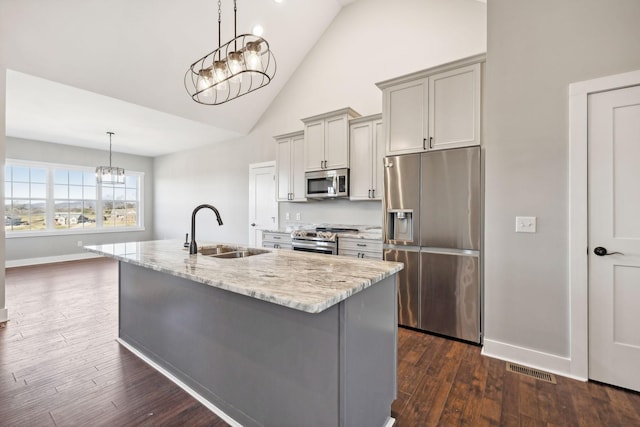 kitchen featuring light stone countertops, sink, stainless steel appliances, and a notable chandelier