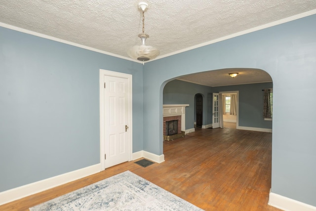 unfurnished room with crown molding, a fireplace, wood-type flooring, and a textured ceiling