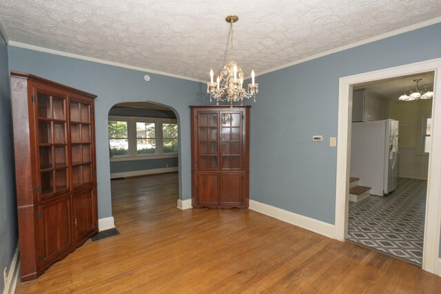 unfurnished dining area with crown molding, a textured ceiling, and light wood-type flooring