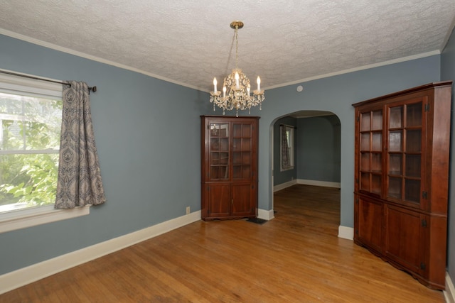 unfurnished dining area featuring a textured ceiling, light wood-type flooring, and crown molding