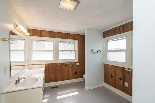 bathroom featuring vanity, a textured ceiling, wooden walls, crown molding, and toilet