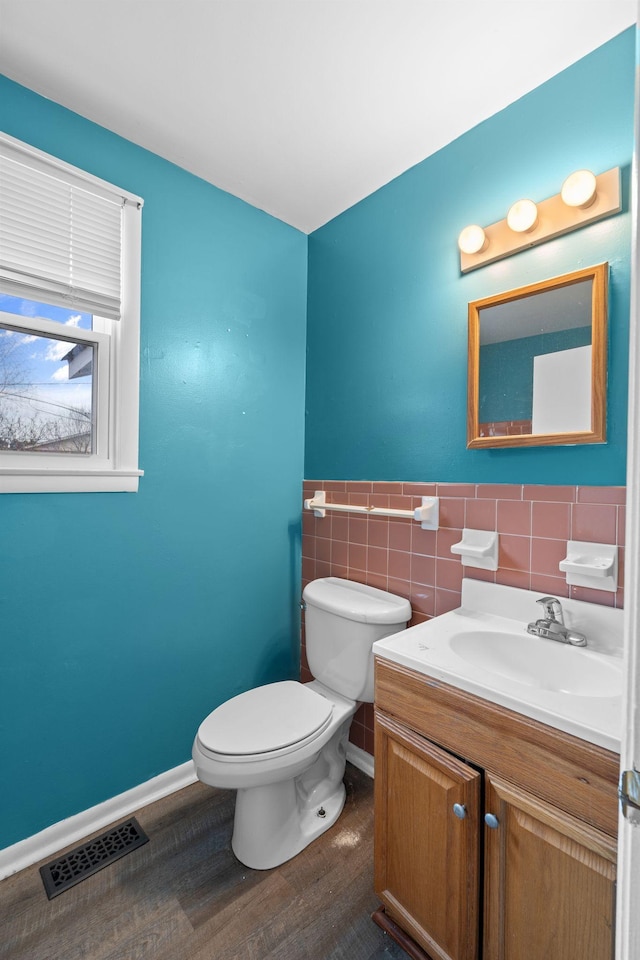 bathroom featuring hardwood / wood-style flooring, vanity, toilet, and tile walls