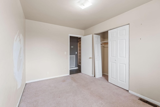 unfurnished bedroom featuring light colored carpet and a closet