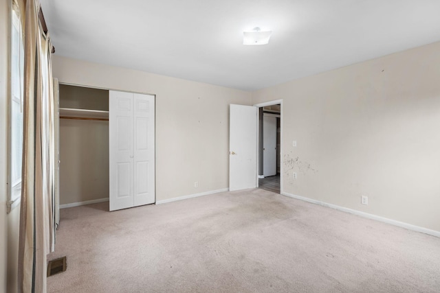 unfurnished bedroom with light carpet and a closet