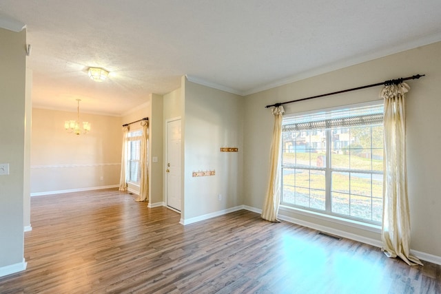 unfurnished room featuring a textured ceiling, crown molding, a notable chandelier, and hardwood / wood-style flooring