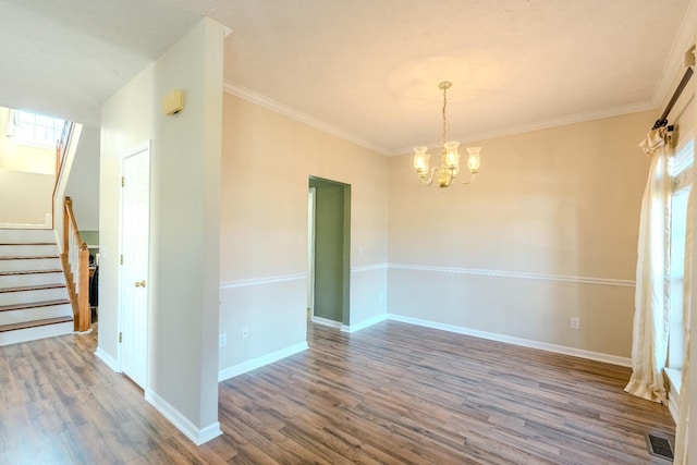 spare room featuring wood-type flooring, ornamental molding, and a chandelier