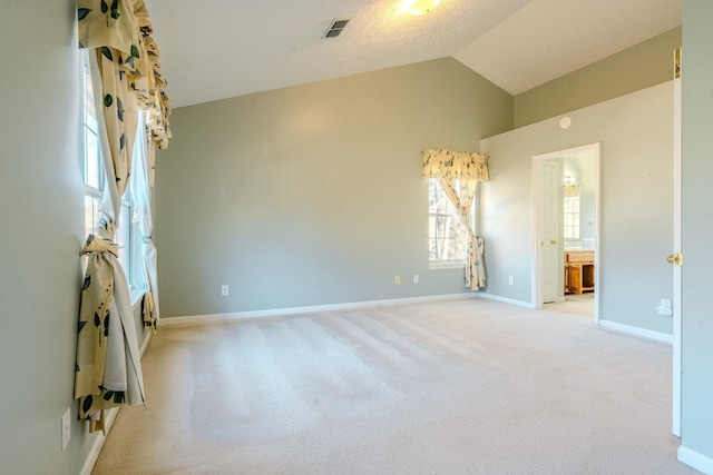 carpeted empty room with lofted ceiling