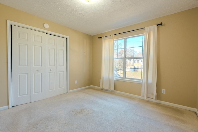 unfurnished bedroom with light colored carpet, a textured ceiling, and a closet