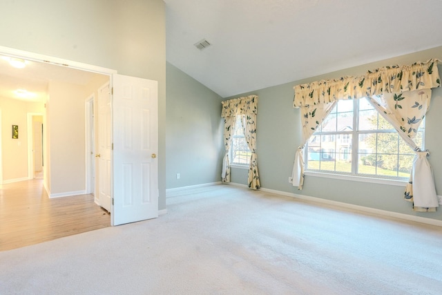 empty room with light hardwood / wood-style flooring and lofted ceiling