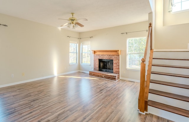 unfurnished living room with ceiling fan, light hardwood / wood-style floors, and a fireplace