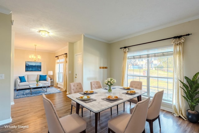 dining area featuring a chandelier, light wood-type flooring, and crown molding