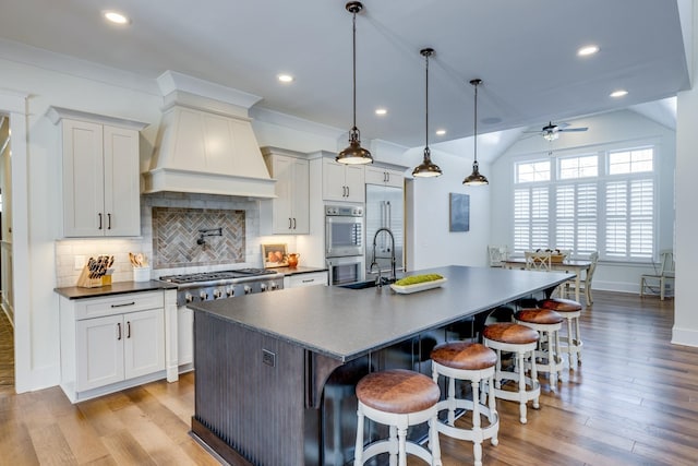 kitchen featuring custom range hood, ceiling fan, light hardwood / wood-style flooring, hanging light fixtures, and a large island