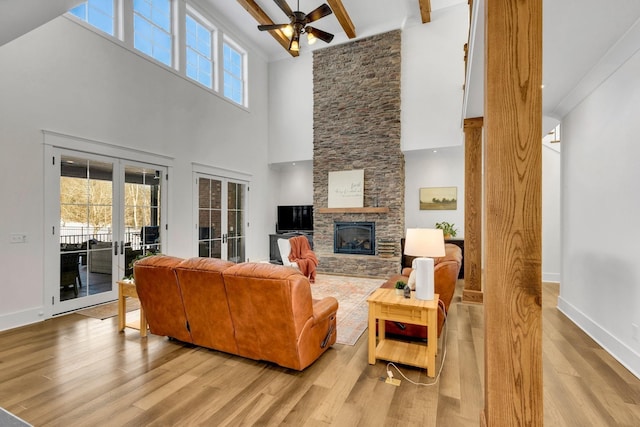 living room featuring french doors, light hardwood / wood-style flooring, ceiling fan, and beam ceiling