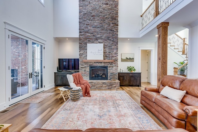 living room with a stone fireplace, light hardwood / wood-style floors, and a high ceiling