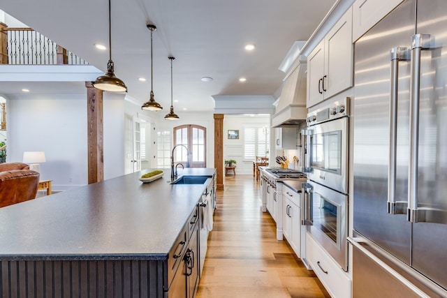 kitchen with sink, stainless steel appliances, a spacious island, white cabinets, and light wood-type flooring