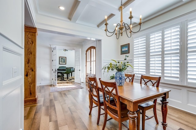 dining space with hardwood / wood-style floors, coffered ceiling, ceiling fan with notable chandelier, crown molding, and beamed ceiling