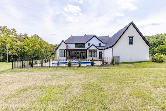 back of property with a lawn, a patio area, and a fenced in pool