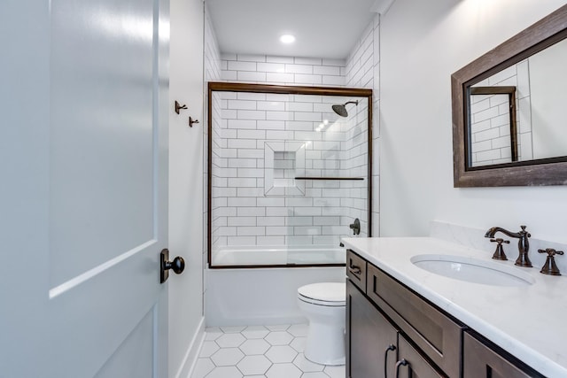 full bathroom featuring tile patterned flooring, vanity, toilet, and bath / shower combo with glass door