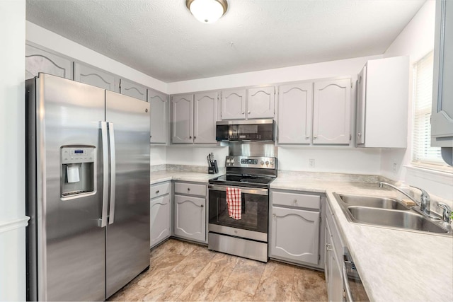 kitchen featuring appliances with stainless steel finishes, gray cabinets, sink, and a textured ceiling