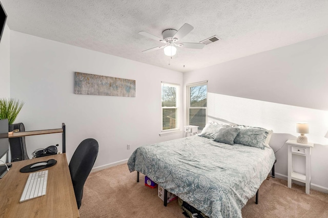 bedroom featuring ceiling fan, light carpet, and a textured ceiling