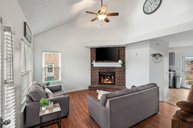 living room with ceiling fan, dark hardwood / wood-style floors, high vaulted ceiling, and a brick fireplace