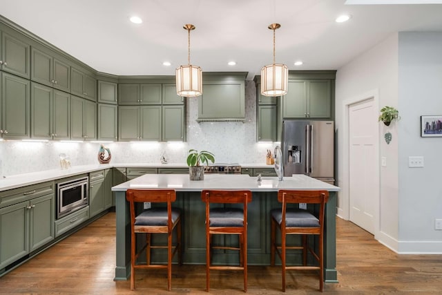 kitchen featuring sink, an island with sink, dark hardwood / wood-style floors, and appliances with stainless steel finishes