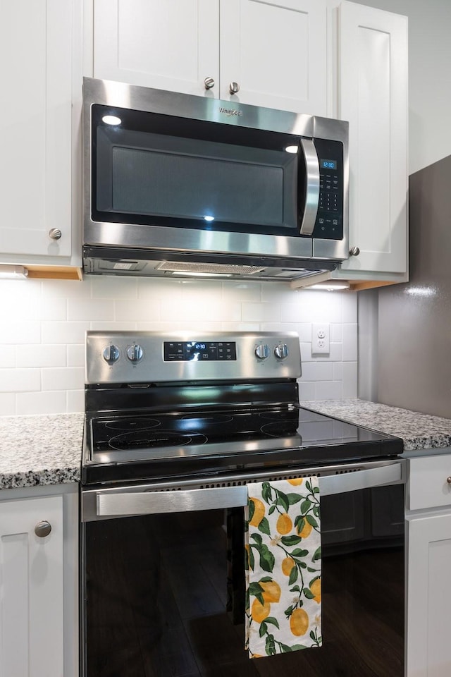 kitchen with light stone counters, white cabinetry, stainless steel appliances, and tasteful backsplash