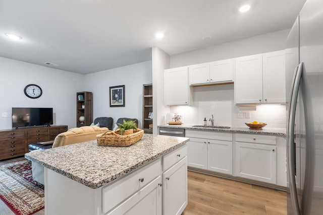 kitchen with sink, white cabinetry, stainless steel appliances, and light hardwood / wood-style flooring