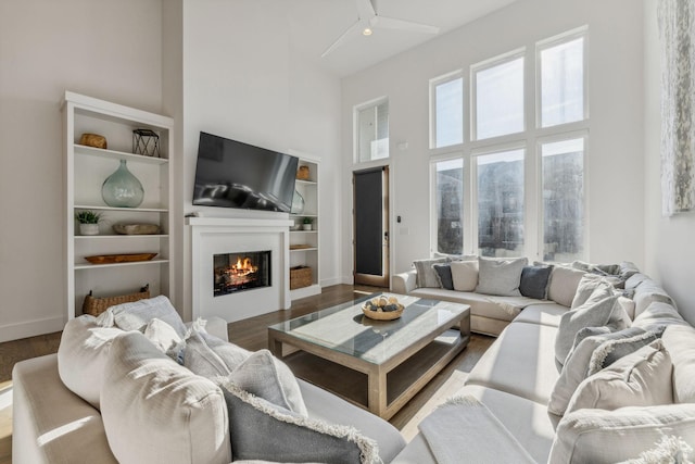 living room featuring hardwood / wood-style floors, ceiling fan, and a high ceiling