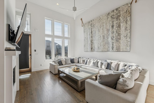 living room featuring ceiling fan, a high ceiling, and hardwood / wood-style flooring