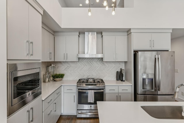 kitchen featuring sink, wall chimney exhaust hood, appliances with stainless steel finishes, dark hardwood / wood-style flooring, and white cabinetry