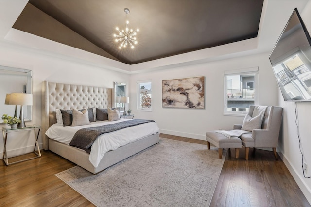 bedroom with a notable chandelier, dark hardwood / wood-style floors, a raised ceiling, and multiple windows