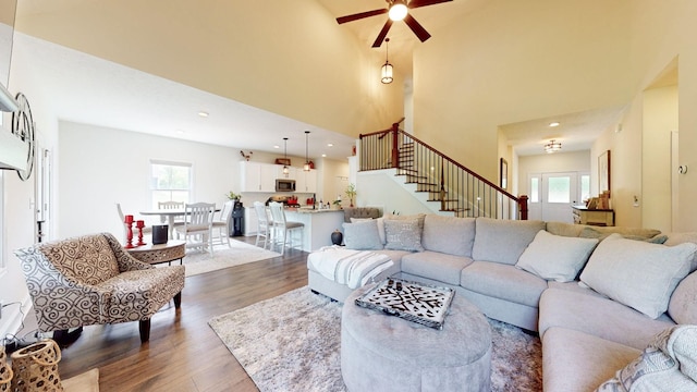 living room with ceiling fan, a high ceiling, and dark hardwood / wood-style floors