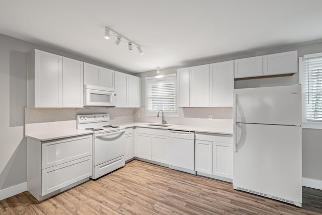 kitchen featuring white cabinetry, sink, white appliances, and light hardwood / wood-style flooring