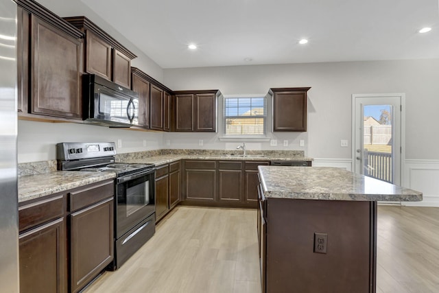 kitchen with dark brown cabinets, sink, light hardwood / wood-style flooring, and black appliances