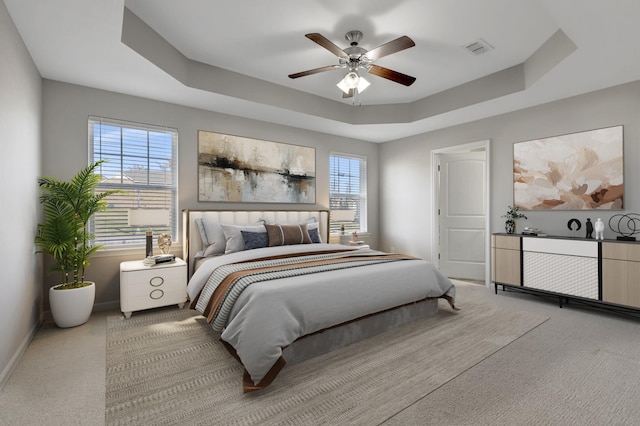 carpeted bedroom featuring a tray ceiling and ceiling fan