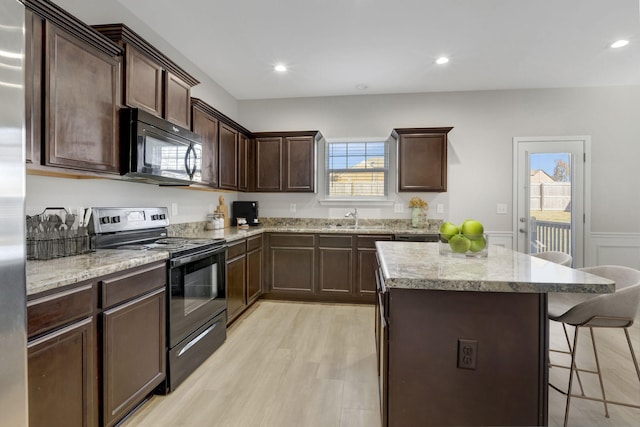 kitchen featuring dark brown cabinets, light hardwood / wood-style floors, stainless steel electric stove, and sink