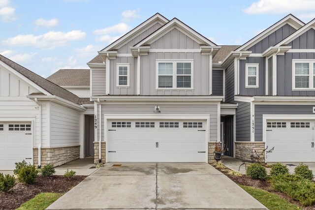 1249 June Wilde Rdg, Spring Hill, TN 37174 - view of front facade featuring board and batten siding, stone siding, driveway, a garage, and a shingled roof