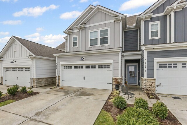 1249 June Wilde Rdg, Spring Hill, TN 37174 - view of front of home with board and batten siding, stone siding, a garage, concrete driveway, and a shingled roof