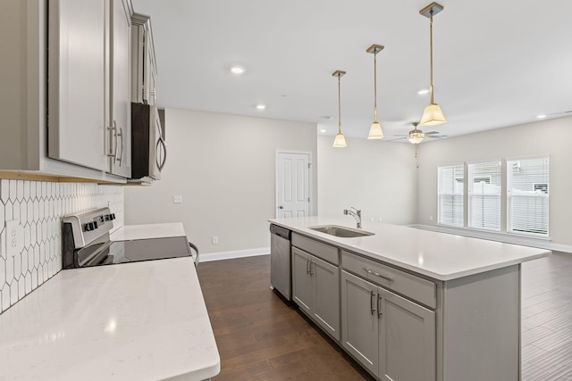 kitchen featuring a center island with sink, range, sink, and hanging light fixtures