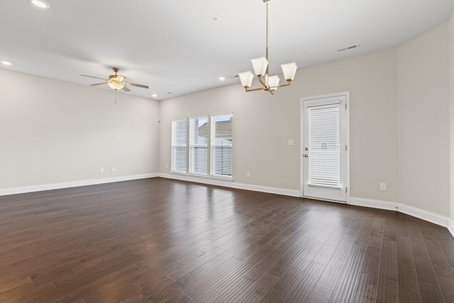 spare room featuring ceiling fan with notable chandelier and dark wood-type flooring