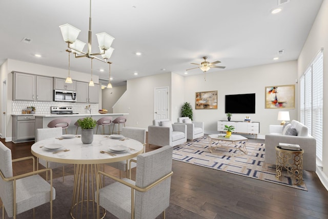 dining room with dark wood-type flooring and ceiling fan with notable chandelier