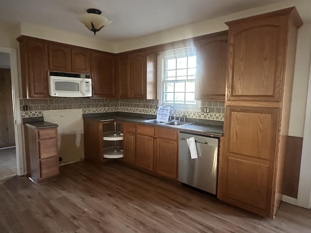 kitchen featuring dishwasher, backsplash, dark wood-type flooring, and sink