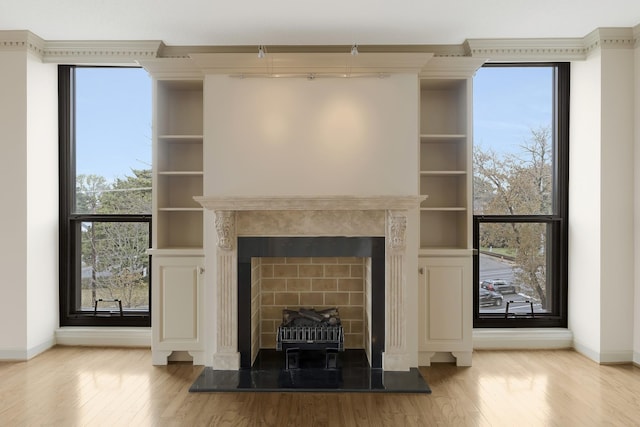 unfurnished living room featuring a tile fireplace, light hardwood / wood-style flooring, and built in shelves